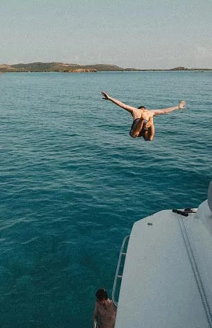 An image of a man diving to water from a yacht